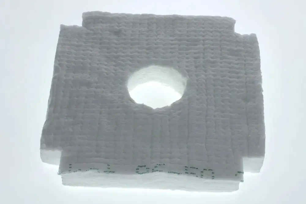 Weißes Isoliermaterial mit rechteckiger Form und zentralem Loch, auf hellem Hintergrund. Zu erkennen ist die Struktur des Materials, das möglicherweise von Bosch stammt.